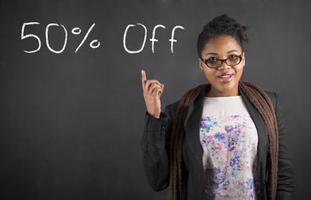 South African or African American black woman teacher or student with a good 50 off idea standing against a chalk blackboard background insideの写真素材
