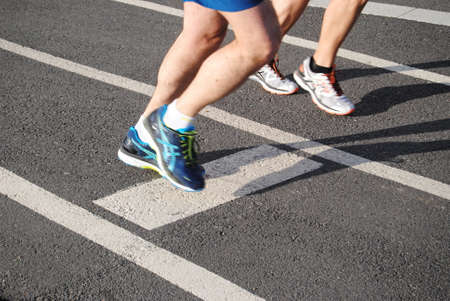 Running - feet of two people running on race track with shoe slippers - playing sports - marathon