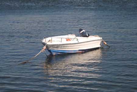 Small white motor boat stopped on the riverの写真素材