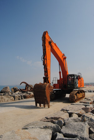Bulldozer and crane head - bucket and claws orange peel with wide digger by the sea