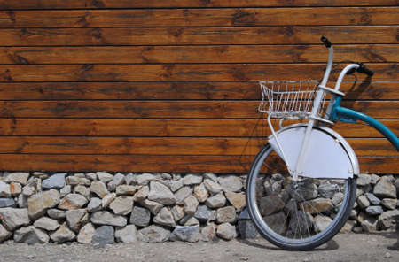 Wooden wall with foundation and stones and a bicycle leaning against the wallの写真素材