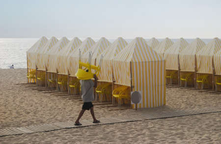 Worker setting up chairs on the beach at sunsetの写真素材