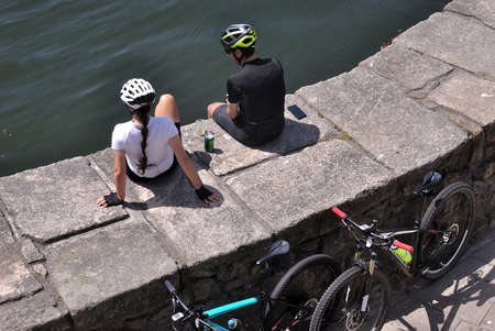 Couple riding a bike by the river, resting