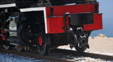 Front of the underside of a metric track steam locomotive, railway line near the sea