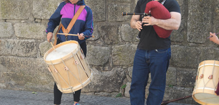 People playing music in the street, a man playing the bagpipes and a girl playing the drumの写真素材