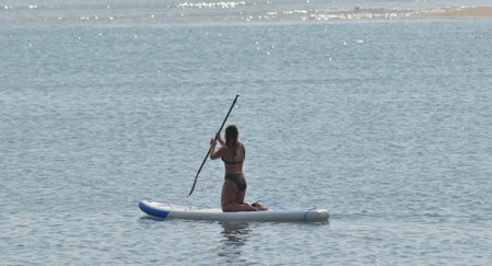 Girl practicing paddle tennis, kneeling on the boardの写真素材