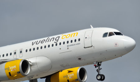 Passenger plane of aviation company of yellow and gray colors prepares for landingのeditorial素材