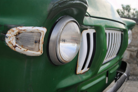 Front of an old stationary green truck, optics, headlights and front grilleの写真素材