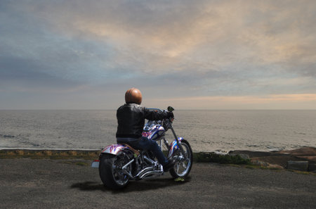 Person riding a bike, stopped, watching the sunset, sea horizon line, relaxing momentの写真素材