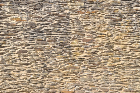 Surface texture of a wall built with small irregular beige stones