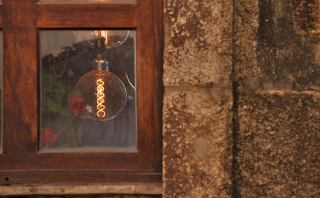 View to the interior of an old house through a glass window, light bulb on, electricity consumption, business, industryの写真素材