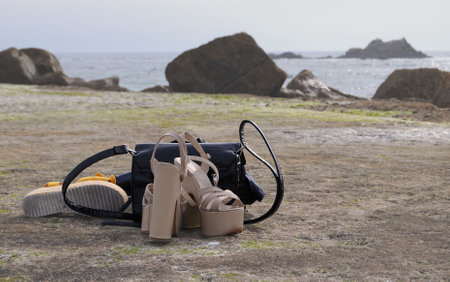 A pair of women's sandals and a bag on the beachの写真素材