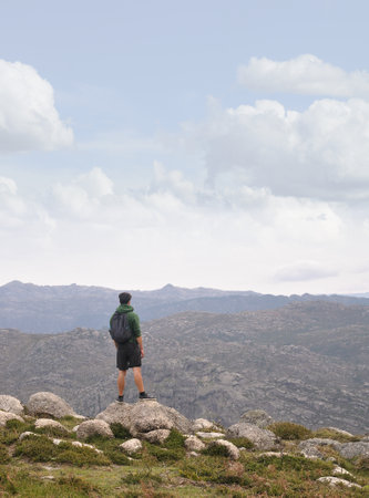 Hiker standing on top of a mountain and looking into the distanceの写真素材