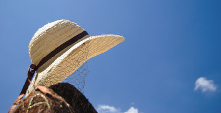 Metallic net molded with a human face shape, a straw hat on a background of the blue sky. Close-up.の写真素材