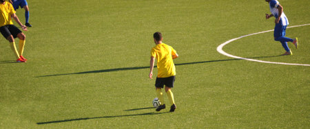 Moment of a football game with a dispute for the ball in the midfield area, yellow, black, blue and white equipmentの写真素材