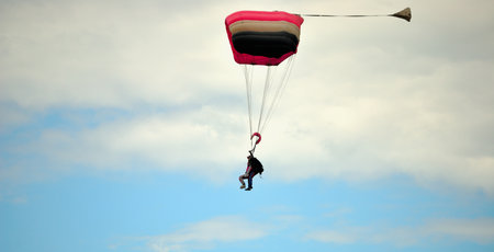 Parachutist flying with a red parachute in the blue sky
