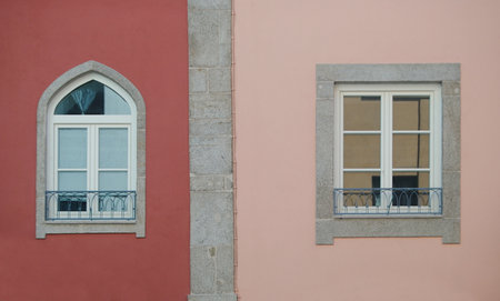 Two windows on a pink wall with a white balcony in the backgroundの写真素材