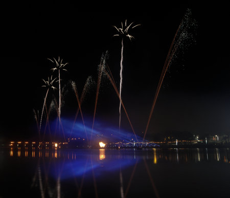 Colorful fireworks of various colors over night sky and water surface.の写真素材