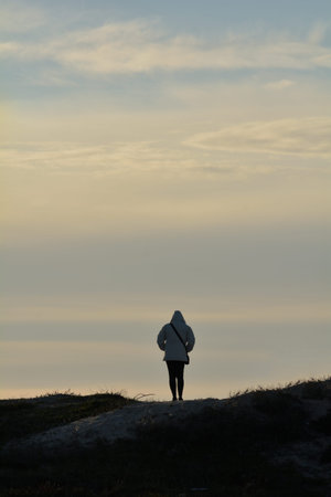 silhouette of a woman staring on the top of a hill at sunset