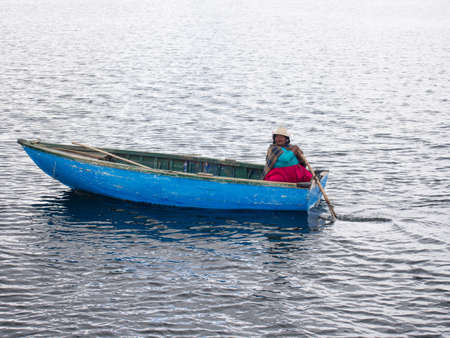 Colorful woman in blue boat on Lake Titicaca in the Reed Islands.のeditorial素材