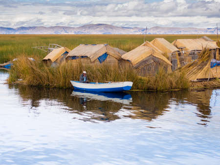 Man in small blue boat in Reed Islands on Lake Titicaca in Peruのeditorial素材