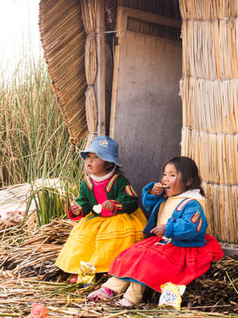 Children in colorful clothing eating in the village in the Reed Islands on Lake Titicaca in Peru.のeditorial素材