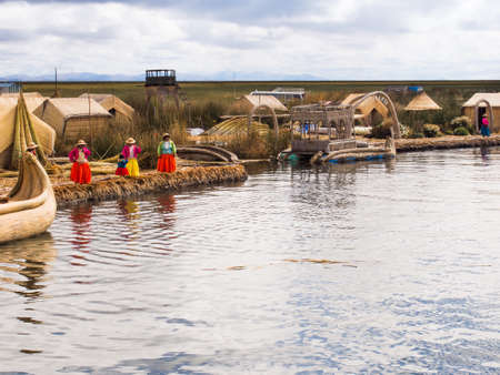 Women in colorful dresses with a child on the pier in the Reed Islands on Lake Titicaca in Peru.のeditorial素材