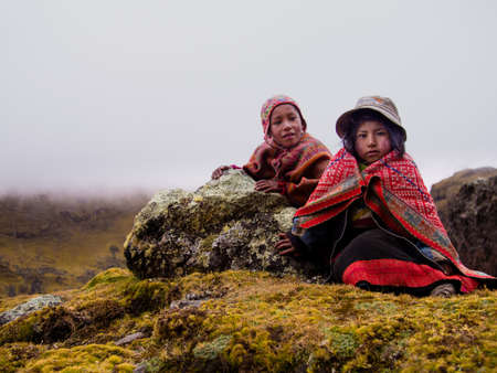 Brother & sister in colorful clothing alone in the Andes mountains of Peru.