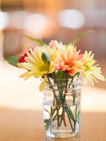 Mixed bouquet in jar on table with bokehの写真素材