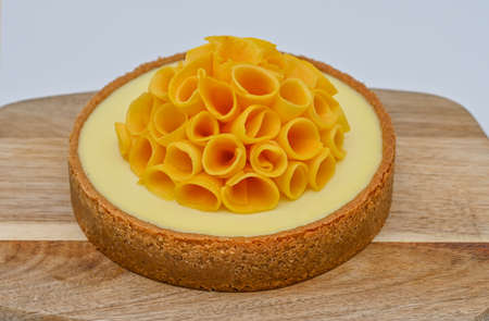 Mango cheese cake on a wooden board decorated with sliced fresh mango