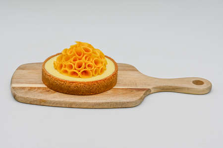 Mango cheese cake on a wooden board decorated with sliced fresh mango