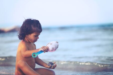 Girl play with shovel in sand on beach. Soft focus.の写真素材