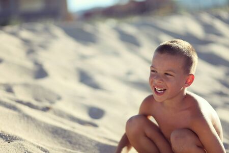 Boy alone in sand on beach with beautiful smileの写真素材