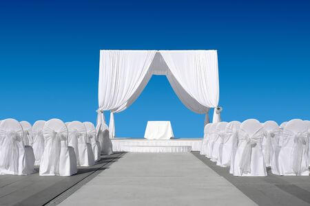 Wedding canopy with chairs, all in white on blue skyの写真素材