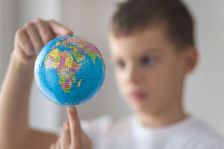 Boy holding toy globus in his hand. Day natural window light.