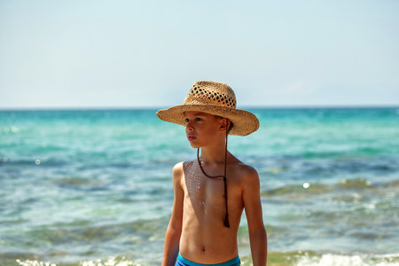 Boy with western hat seriously looking around in summerの写真素材