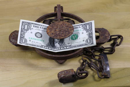 Money Trap, US money as bait on foothold trap, on textured wood background