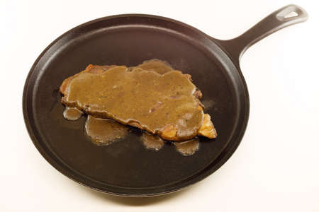 Ham steak with red-eye gravy served on a cast iron skillet. Isolated on a white backgroundの写真素材
