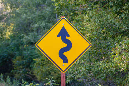 Road sign indicating curves ahead. Selective focus, background and foreground blur.の写真素材