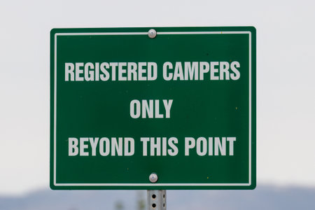 Green sign with white letters in a campground indicating only registered campers are allowed beyond that point.の写真素材