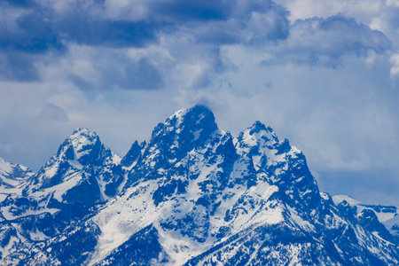 Landscape view of the snow covered peaks of Grand Teton, Middle Teton and Mount Owen with heavy cloud cover in Grand Teton National Park, Wyoming, USAの写真素材