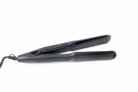 Electric curling iron with ceramic plates isolated on white background. Black hair straightener with ceramic plates isolated on white backgroundの写真素材