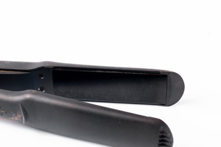 Electric curling iron with ceramic plates isolated on white background. Black hair straightener with ceramic plates isolated on white backgroundの写真素材