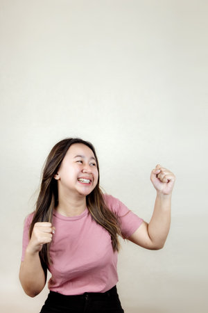 Portrait of an attractive young Asian woman shouting success, joy and victory with clenched fists.の写真素材