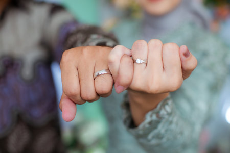 The bride and groom exchange rings at the wedding. A husband and wife put rings on each other's fingers. Holding a wedding ring. Precious metal jewelry for married couples.の写真素材