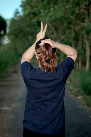 Clothing model. Young Asian woman with sunglasses posing outdoors. Asian woman wearing a plain Navy Blue t-shirt on a background of trees. It was as if he was modeling a plain t-shirt.の写真素材