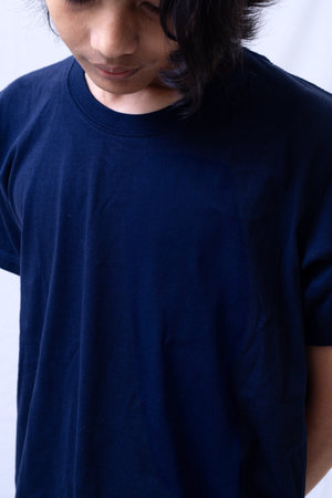 Clothing model. Young Asian man with long curly hair close up shot isolated on white. Asian young man wearing navy blue t-shirt isolated on white background. As if he were modeling a plain t-shirt.の写真素材