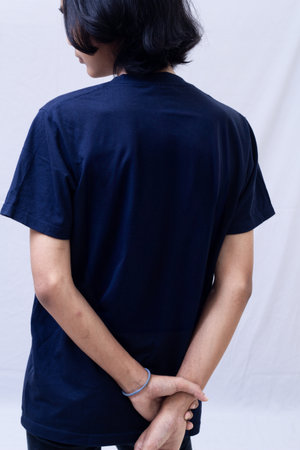 Clothing model. Young Asian man with long curly hair close up shot isolated on white. Asian young man wearing navy blue t-shirt isolated on white background. As if he were modeling a plain t-shirt.の写真素材