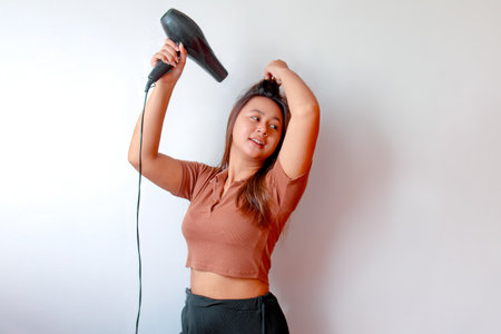 Young Asian woman holding a hair dryer and using the hair dryerの写真素材