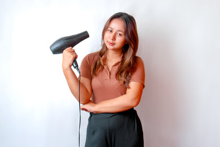 Young Asian woman holding a hair dryer and using the hair dryerの写真素材
